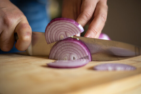 man hands cutting red onion close up on wooden board