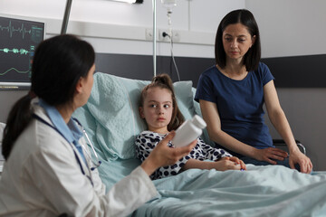 Doctor expert recommending antibiotics for ill kid sickness hospitalized in children healthcare facility. Expert pediatrician prescribing medication for little girl disease resting in patient bed.