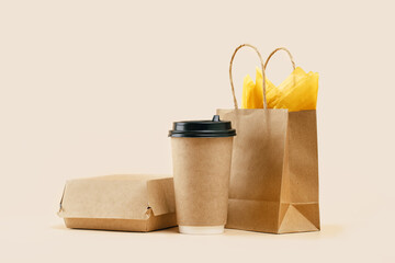 Takeaway paper coffee cup with lunch bag and burger box on beige. Snack delivery service. Coffee to...