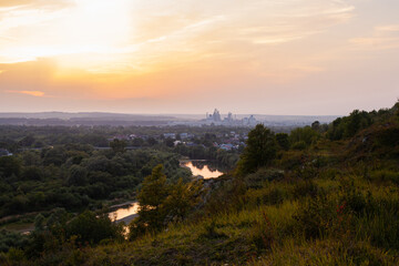 Fototapeta na wymiar Panoramic view of the city of Ivano-Frankivsk. View of mountain hill and industrial power station oland behind at evening. Sunset over Ivano Frankivsk city in Ukraine. Landscape with hills and river.