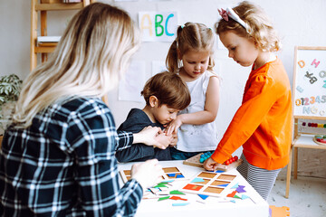 Naughty boy take away and keep detail of constructor. Child not sharing toys with other kids. Educator try to resolve conflict. Children play with educational games in lesson in kindergarten