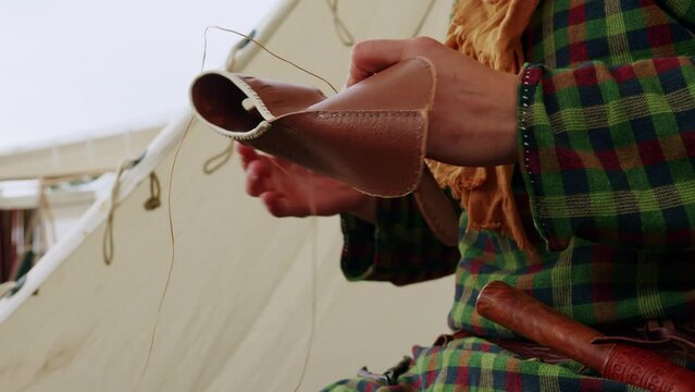 Static close up of a man manual stitching making a leather traditional and medieval shoe