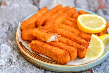Close up of   Crispy breaded  deep fried fish fingers with breadcrumbs served  with remoulade sauce and  lemon Cod Fish Nuggets on rustic wood table background