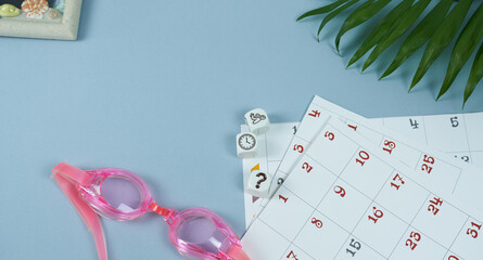 Calendar with pink bathing goggles, photo frame and cubes. The concept is time planning.