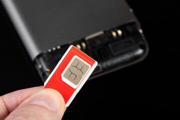 A man holding sim card against the background of a smartphone
