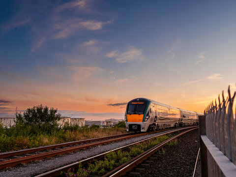 Galway, Ireland 31.08.2022: Irish Rail train at sunset near train station. Transport and commute. Calm and peaceful mood. Warm and cool color.