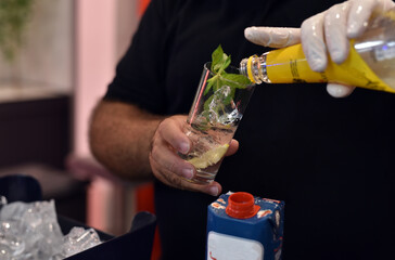 The male bartender offers the drinks he has prepared to the party participants