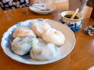 Various Chinese dumpling with seasoning on wooden table