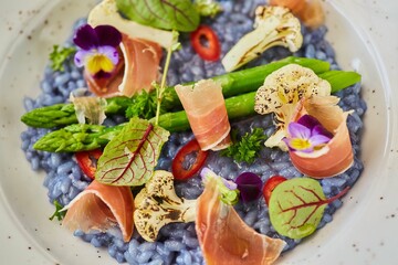 Blue risotto with asparagus and bacon. Food from the chef in a restaurant or cafe.