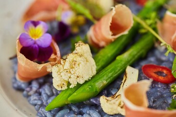 Blue risotto with asparagus and bacon. Food from the chef in a restaurant or cafe.