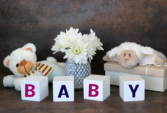Das Wort Baby aus Buchstabenwürfel mit Spielzeug und Teddybär. 
