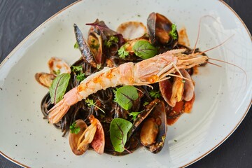 Black pasta with mussels and king shrimp. Food from the chef in a restaurant or cafe.