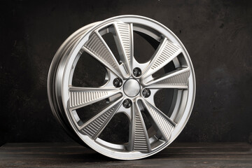 new grey alloy wheels on a dark textured black background. a wheel for a car