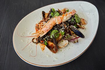 Black pasta with mussels and king shrimp. Food from the chef in a restaurant or cafe.