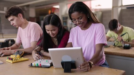 Multiracial group of high school students programming electronic circuits at technology class