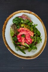 Salad of greens, red fish and broccoli. Food from the chef in a restaurant or cafe.