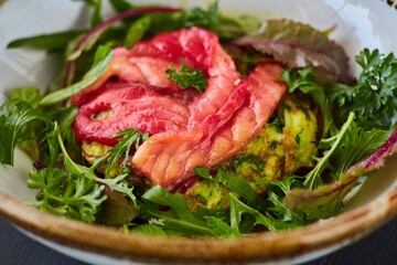 Salad of greens, red fish and broccoli. Food from the chef in a restaurant or cafe.
