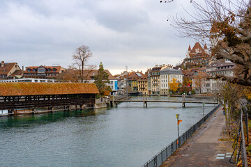 Obraz premium Nice view along Aare lake and wooden bridge in old town of Thun during autumn , winter cloudy day : Thun , Switzerland : December 2 , 2019