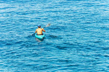 Young adult man, 30-35 years, paddle in the blue Mediterranean sea on a kayak. Tellaro village, Lerici municipality, Gulf of La Spezia, Liguria, Italy, Europe.
