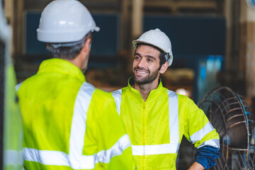 Caucasian factory engineer talking and shaking hands on business cooperation agreement. Successful hand shaking after good deal, workers handshaking each other at heavy industrial production line.