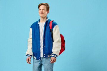 horizontal portrait of a handsome, joyful student guy with a red backpack on his shoulder, looking at the camera