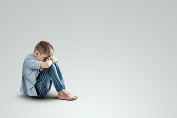 Stress, depression, emotional burnout. Malchi, the child sits with his head down on his knees, sad....