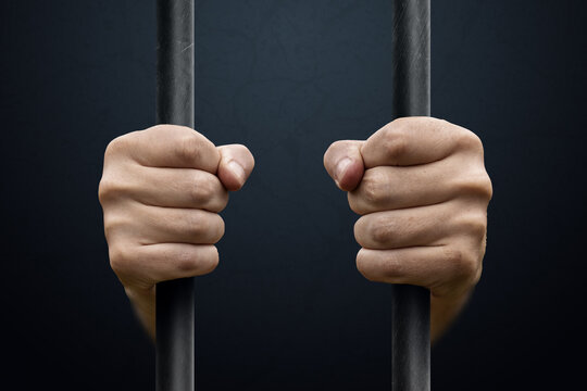 Man's hands behind bars. justice, punishment, imprisonment, court, prison.