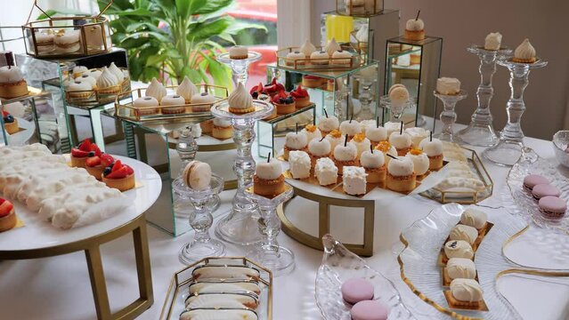 White Candy Bar Wedding Catering. Candy buffet, delicious sweet snacks, candy bar with cupcakes, cakepops, macaroons, cake, bize and other sweets cookies Banquet Hall. Event. Business Party. Birthday.