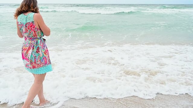 Mature woman flees from the waves of the sea on a cloudy day