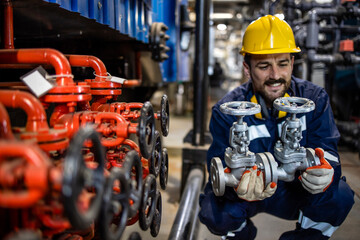 Industrial maintenance service and experienced engineer changing pipe valves in oil refinery plant.