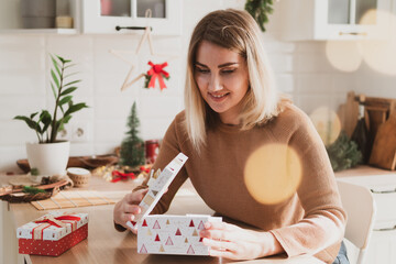 Obraz na płótnie Canvas Attractive woman sitting in the kitchen with New Year and Christmas gifts in beautiful interior