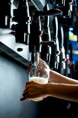 Beer is poured from the tap into the glass. Close-up, selective focus. Noise added in...
