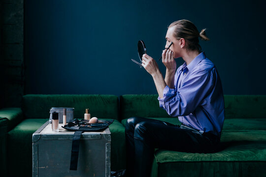 Make-up artist applying eyeshadow looking in hand mirror