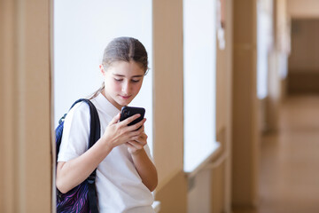 student looks at phone in school hall. child teenager and gadget