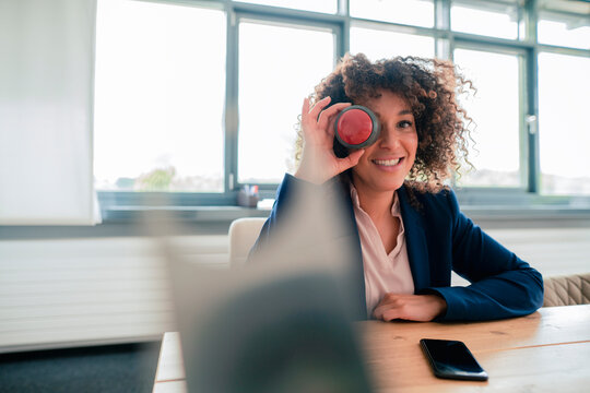 Businesswoman with buzzer button covering eye at office