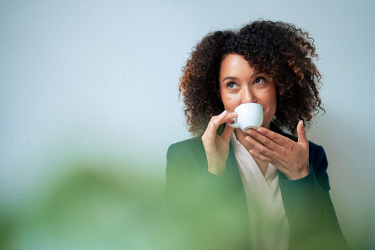 Mature businesswoman drinking coffee in front of wall