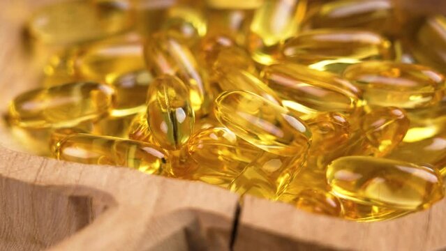 Yellow Omega 3 capsules in a cracked wooden bowl. Health Supplement. Rustic style view. Rotation