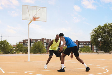 Father playing basketball with son defending at court