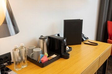 Coffee machine, tea kettle and water bottles on a table in hotel room