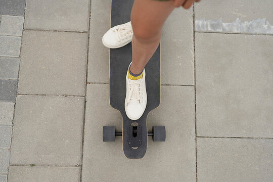 Girl standing on skateboard at footpath