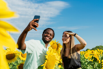 Happy man with woman taking selfie through mobile phone in sunflower field