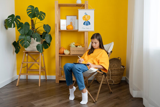 Girl using tablet PC sitting on chair at home