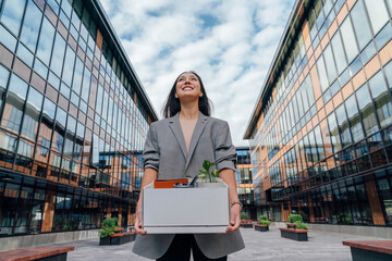 Happy businesswoman carrying box in front of office building