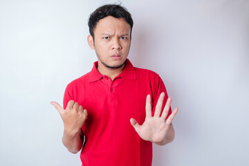 Attractive Asian man with hand gesture pose rejection or prohibition while pointing to copy space...