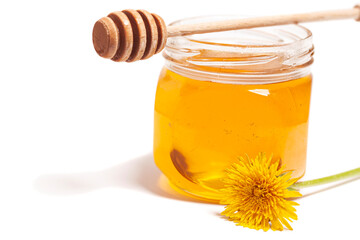 Honey dripping from honey dipper in glass jar with dandelion. Healthy food concept