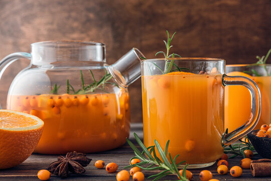 Sea buckthorn autumn tea with orange in glass cups with fresh berries, cinnamon and rosemary. Hot autumn drink