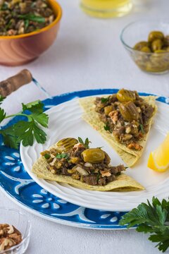 An appetizer, a salad of baked eggplant, onions, herbs and spices on tortillas on a white plate on a light concrete background. Recipes for eggplant.