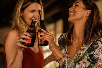 Naklejka na ściany i meble Two young women enjoying a beer together
