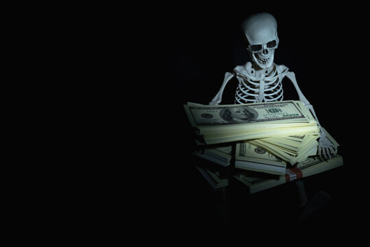 Funny image of skeleton skull with US Dollar money as symbol of wealth and greed. Copy space.