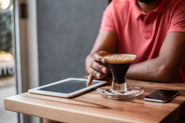 African American businessman working in coffee shop and using technology
